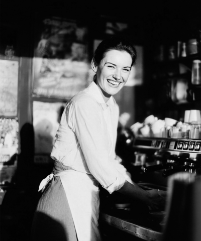Barista Frau im Café lächelt in die Kamera Frau-im-Cafe-Barista.png